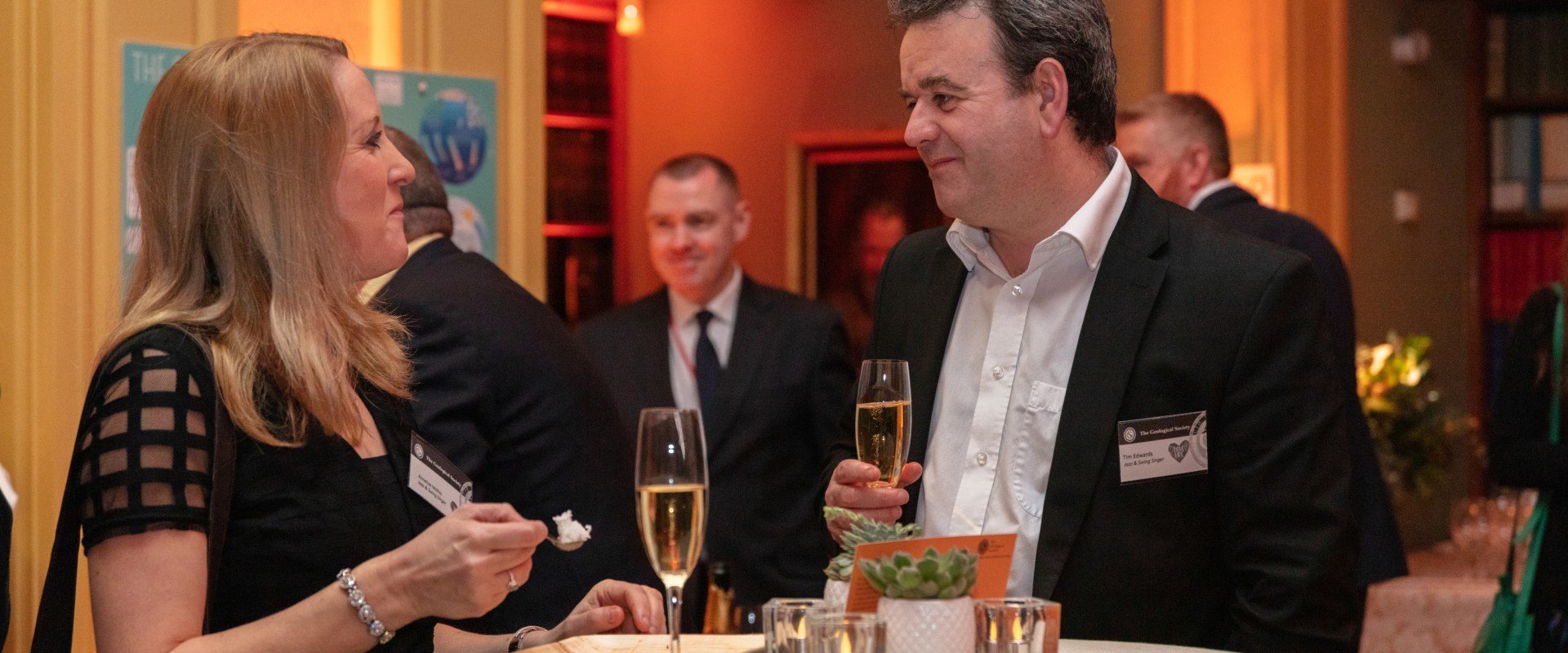 white man and white woman chatting with glasses of champagne in their hands