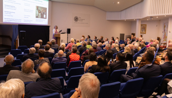 People seated in a lecture theatre listening to a woman speaking