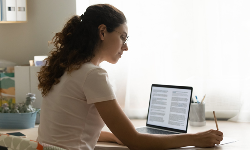 Image: individual person working at a desk with open laptop