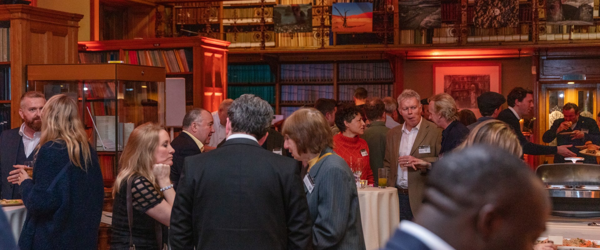 people attending an event in a library with buffet food on a table