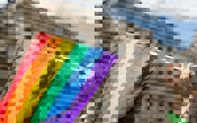 a hand holding a rainbow flag