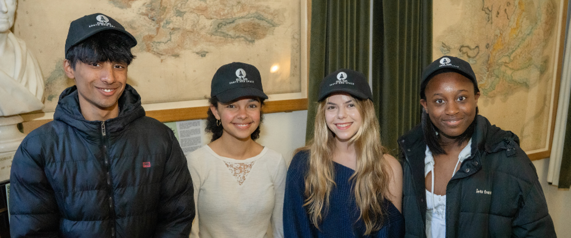 Two young black girls and one young white girl and one young Asian boy smiling at the camera